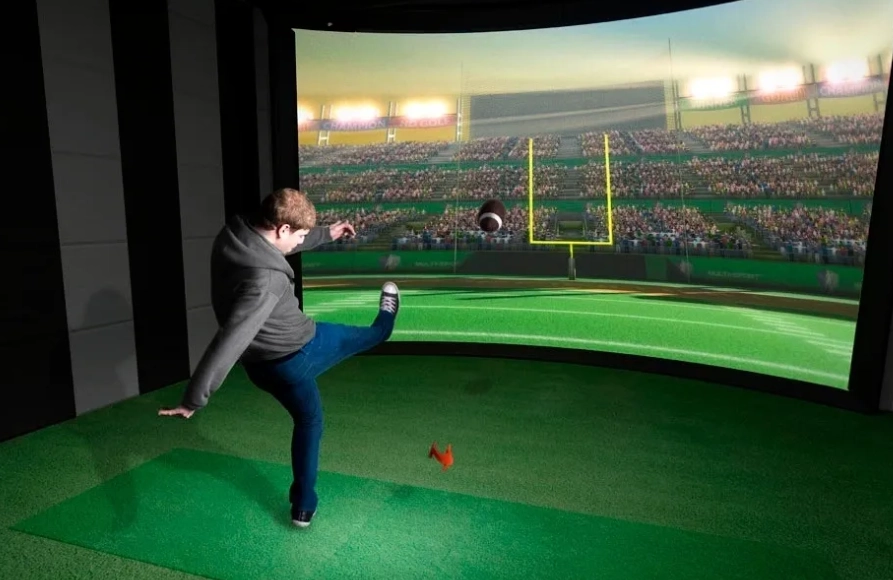 A man kicking a ball in front of an image of a stadium.