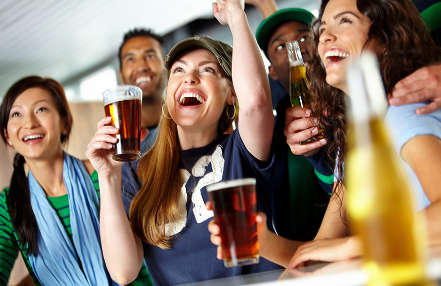 A group of people holding beers and raising their hands.