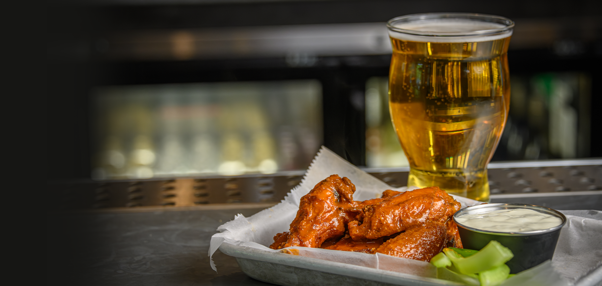 A plate of chicken wings and a glass of beer.