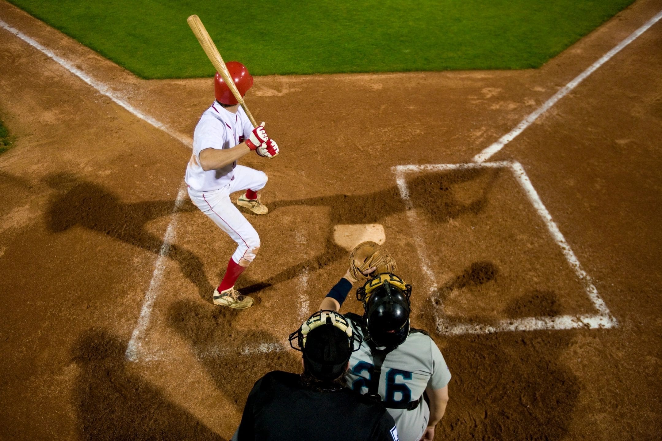 A baseball player swinging at the ball while another player catches it.